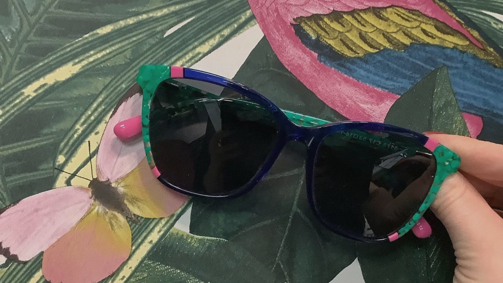 Colourful Cocoa Mint sunglasses against tropical parrot wallpaper
