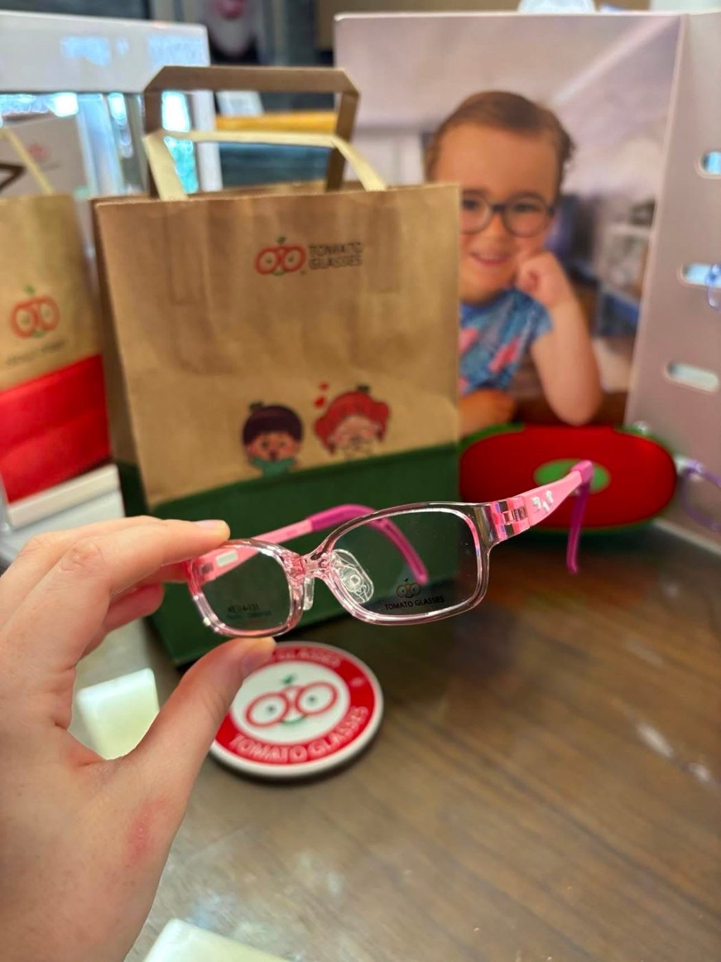 A toddler with pink Tomato Glasses and their gift bag