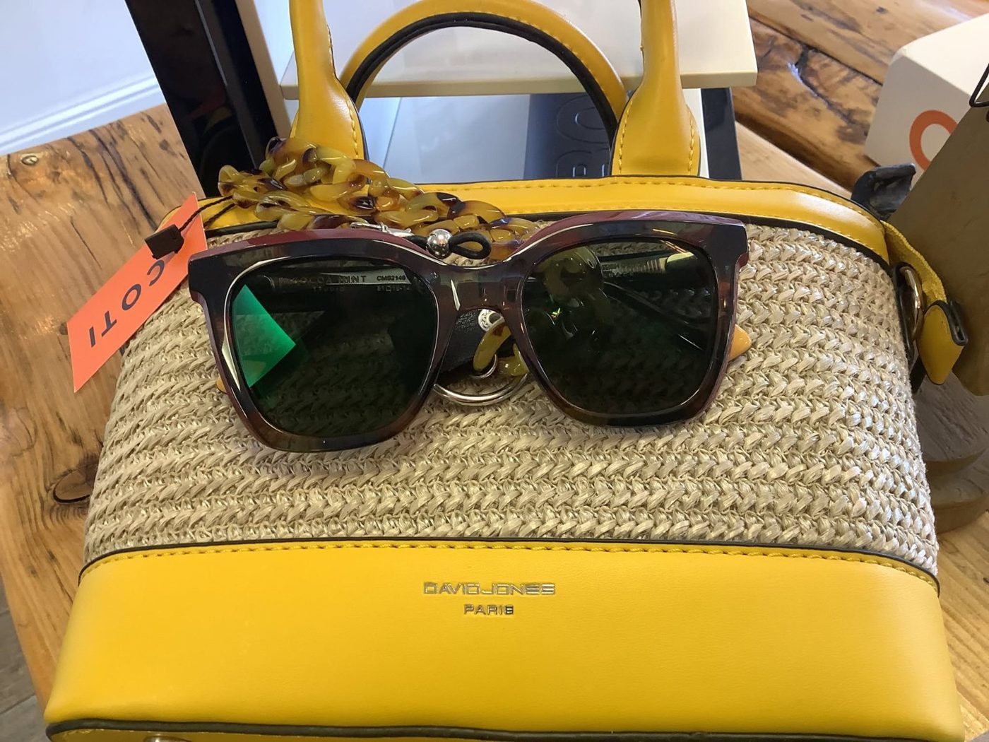 Tortoiseshell sunglasses resting on a straw handbag
